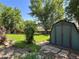 Spacious backyard with a shed, mature trees, and lush green grass, perfect for outdoor activities and storage at 8296 S Reed St, Littleton, CO 80128