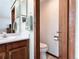 A half bathroom featuring wood cabinets, a white countertop with a sink, a mirror, and a toilet at 8296 S Reed St, Littleton, CO 80128