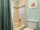 Bathroom with ceramic tile shower, framed art, a modern toilet, and a green curtained bathtub at 8296 S Reed St, Littleton, CO 80128