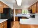 Functional kitchen features ample wood cabinetry, black appliances, and solid surface countertops at 8296 S Reed St, Littleton, CO 80128