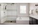 Bright bathroom with a tiled shower, soaking tub, and dark cabinets at 6072 Chester St, Denver, CO 80238