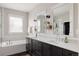 Bathroom featuring double vanity sinks, a soaking tub, and modern fixtures at 6072 Chester St, Denver, CO 80238
