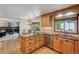 Open kitchen with stainless steel dishwasher, wooden cabinets, and breakfast bar overlooking the living area at 7312 S Moore Ct, Littleton, CO 80127
