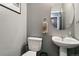 Clean half bathroom featuring a pedestal sink, round mirror, and neutral paint at 9919 Memphis St, Commerce City, CO 80022