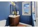 Stylish powder room with blue walls, dark wood vanity, gold mirror, and a window at 26531 E Calhoun Pl, Aurora, CO 80016