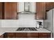 Modern kitchen featuring stainless steel vent hood, gas range, white backsplash, and white countertops at 26531 E Calhoun Pl, Aurora, CO 80016