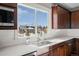 Bright kitchen with stainless steel sink, white backsplash, wooden cabinetry and view of neighborhood at 26531 E Calhoun Pl, Aurora, CO 80016