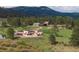 Estate with modern house, pond, outbuildings, trees, lush grounds, and mountain backdrop at 28098 Green Valley Ln, Conifer, CO 80433