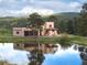 Tan two-story home reflected in a pond with mature landscaping and mountain views at 28098 Green Valley Ln, Conifer, CO 80433
