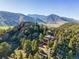Overhead shot capturing a luxury home surrounded by trees and stunning mountain views in the distance at 9041 Eastridge Rd, Golden, CO 80403