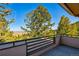 Outdoor balcony with wood deck overlooking lush trees, creating a tranquil space to relax and enjoy the beautiful landscape at 9041 Eastridge Rd, Golden, CO 80403