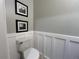 Well-appointed powder room featuring classic wainscoting, white toilet, framed pictures and light gray walls at 5724 S Rome St, Aurora, CO 80015