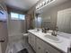Bright bathroom with a double sink vanity, updated fixtures, gray tiling and a large mirror at 5724 S Rome St, Aurora, CO 80015