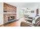 Open-concept room showcasing a brick fireplace, hardwood floors, and a dining area with backyard access at 9630 W 104Th Ave, Broomfield, CO 80021