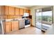 Kitchen with wood cabinets, stainless steel appliances, and balcony access at 1200 N Humboldt St # 1103, Denver, CO 80218