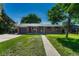 Inviting brick home with green shutters, manicured lawn, and an expansive front yard under a sunny sky at 7479 Pierce St, Arvada, CO 80003