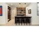 Basement bar with black counter, barstools, glass shelving, and modern lighting at 20 Viking Dr, Cherry Hills Village, CO 80113
