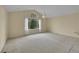 Bedroom with vaulted ceiling, neutral carpet, and a large arched window overlooking mature trees at 18142 E Oakwood Pl, Aurora, CO 80016