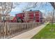 Charming red brick building featuring well-maintained landscaping and a rustic wooden fence at 124 E Colorado Ave # 2, Denver, CO 80210
