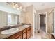 Spacious bathroom with double sinks, wood cabinets, granite countertops, walk-in closet, tiled floors, and updated fixtures at 7506 Sabino Ln, Castle Rock, CO 80108