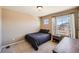 Bedroom with neutral walls and carpet features a window with curtains, and a dark bed with a wooden side table at 7506 Sabino Ln, Castle Rock, CO 80108