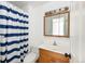 The well-lit bathroom offers a wood vanity with an updated light fixture and a blue and white shower curtain at 11381 Jay St, Westminster, CO 80020