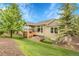 Expansive backyard featuring lush green lawn, mature trees, a wooden deck, and well-maintained landscaping at 1033 Bramblewood Dr, Castle Pines, CO 80108