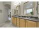 Well-lit bathroom with double sinks, tile backsplash, vanity with wood cabinets, and natural light at 1033 Bramblewood Dr, Castle Pines, CO 80108