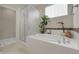 Bright bathroom featuring a soaking tub, separate shower, tile surround, neutral walls, and large tile flooring at 1033 Bramblewood Dr, Castle Pines, CO 80108