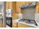 This kitchen has stainless steel appliances, stylish backsplash, wood cabinets, and light countertops at 1033 Bramblewood Dr, Castle Pines, CO 80108