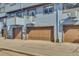 Townhome featuring multiple garage doors and light blue wood siding at 8911 W Yale Ave, Lakewood, CO 80227