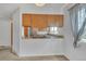 Kitchen pass through with granite countertops, wooden cabinets, a stainless steel sink, and natural light at 8911 W Yale Ave, Lakewood, CO 80227
