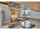 Kitchen featuring stainless steel appliances, granite countertops, wooden cabinets, and a view of trees at 8911 W Yale Ave, Lakewood, CO 80227