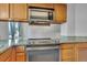 Kitchen area featuring granite counters, stainless steel stove, microwave, and wooden cabinets at 8911 W Yale Ave, Lakewood, CO 80227