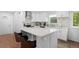 Open kitchen showcasing modern white cabinetry, stainless steel appliances, and a kitchen island with chairs at 23 S Nome St # A, Aurora, CO 80012