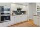 Modern kitchen with stainless steel appliances, granite counters, white cabinets, and stylish tile backsplash with hardwood floor at 10155 Riverstone Dr, Parker, CO 80134