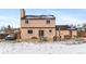 Back of house with stucco, patio, hot tub, wood pile and snow in the yard at 1206 Baldwin Park Cir, Castle Rock, CO 80104