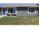 Charming home exterior with new gray siding, manicured lawn, flowerbed, and a cute chair set on the front porch at 951 Paris St, Aurora, CO 80010