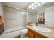 Modern bathroom with an enclosed shower-tub, oak vanity, and well-lit vanity mirror at 6617 S Reed Way # C, Littleton, CO 80123