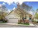 Charming home featuring a two-car garage, stone accents, and beautiful landscaping under a partly cloudy sky at 6617 S Reed Way # C, Littleton, CO 80123
