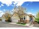 Charming home featuring a two-car garage, stone accents, and beautiful landscaping under a partly cloudy sky at 6617 S Reed Way # C, Littleton, CO 80123