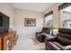 Cozy living room featuring plush armchairs, a window with decorative valance, and a wooden media cabinet at 6617 S Reed Way # C, Littleton, CO 80123