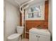 Clean basement bathroom with white toilet and sink, brick feature wall, and window at 3750 S Ogden St, Englewood, CO 80113