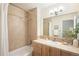Well-lit bathroom featuring a shower-tub combo, a framed mirror, and wood cabinets at 2910 S Racine St, Aurora, CO 80014
