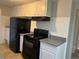 Kitchen area featuring black appliances, including a refrigerator and stove, with white cabinets at 4785 Estes St, Wheat Ridge, CO 80033