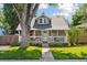 Charming home featuring a cozy front porch, well-manicured lawn, and a large tree providing shade at 3976 S Washington St, Englewood, CO 80113
