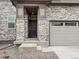 Inviting entryway features a stone facade, covered porch, and a stylish front door with side window and two car garage at 559 Homestead Ave, Brighton, CO 80601
