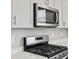 Close up of stainless steel microwave and gas range with sleek gray cabinets at 559 Homestead Ave, Brighton, CO 80601