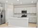 Modern kitchen featuring white cabinets, a center island, stainless steel appliances, and wood flooring at 559 Homestead Ave, Brighton, CO 80601