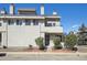 View of a townhouse with neutral stucco exterior, mature landscaping, and a private balcony on the second floor at 1830 Newland Ct # 101, Lakewood, CO 80214